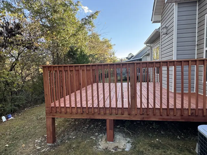 Stained deck seen from the yard beside gray siding in Chattanooga, TN
