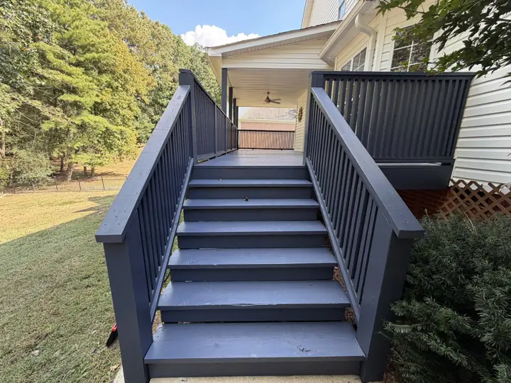 Wide deck stairs and railings in solid charcoal-gray stain leading to a covered porch in Hixson, TN