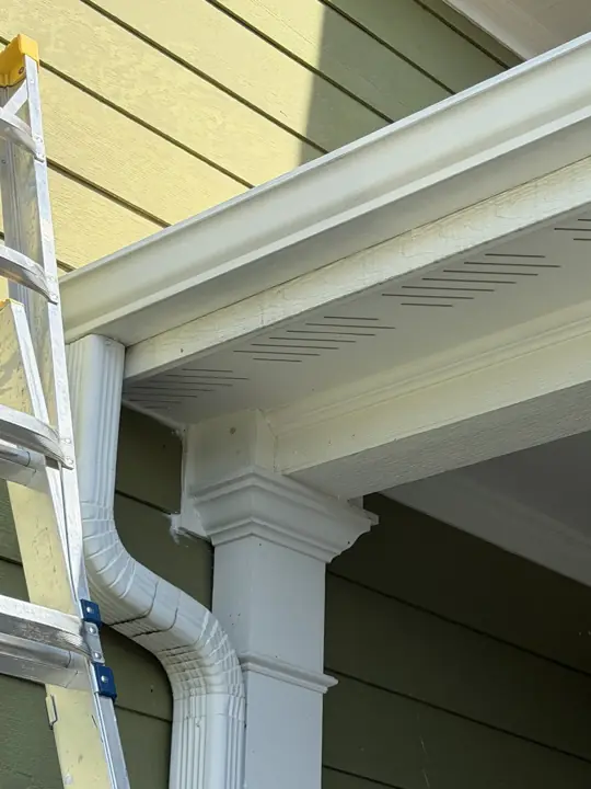 Ladder at the gutter line during trim prep on olive-green siding in Ooltewah, TN