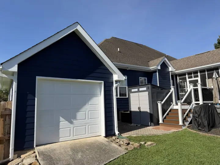 Detached garage with navy siding and white gable trim beside a painted house in Ooltewah, TN
