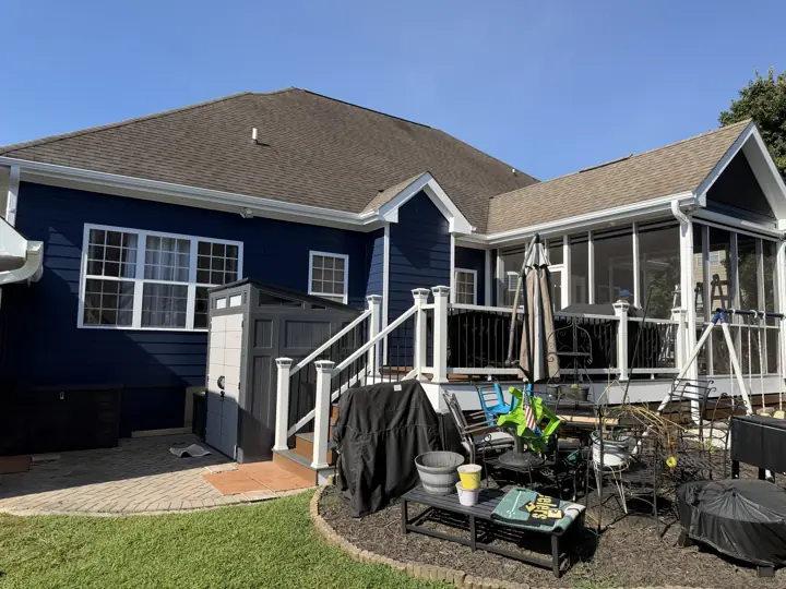 Back of a navy-sided home with white deck railings and screened porch in Ooltewah, TN