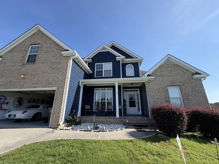 Brick and navy siding facade with white gables and porch columns after exterior painting in Ooltewah, TN