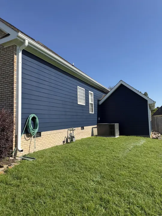 Navy lap siding above a brick foundation with white downspout and trim in Ooltewah, TN