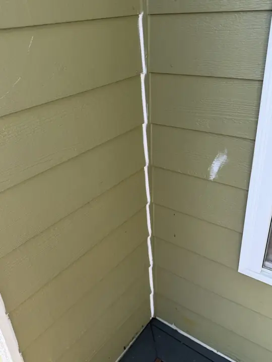 Fresh caulk along an olive-green siding corner before repainting in Ooltewah, TN