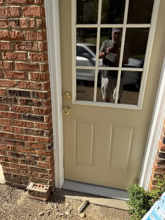 Back door painted tan with white casing set in red brick in Signal Mountain, TN