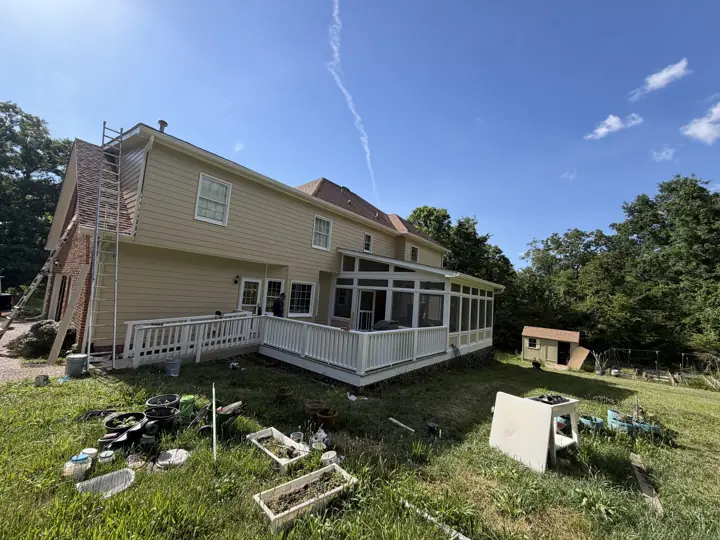 Wide view of tan siding, white railings and screened porch with ladder still up in Signal Mountain, TN
