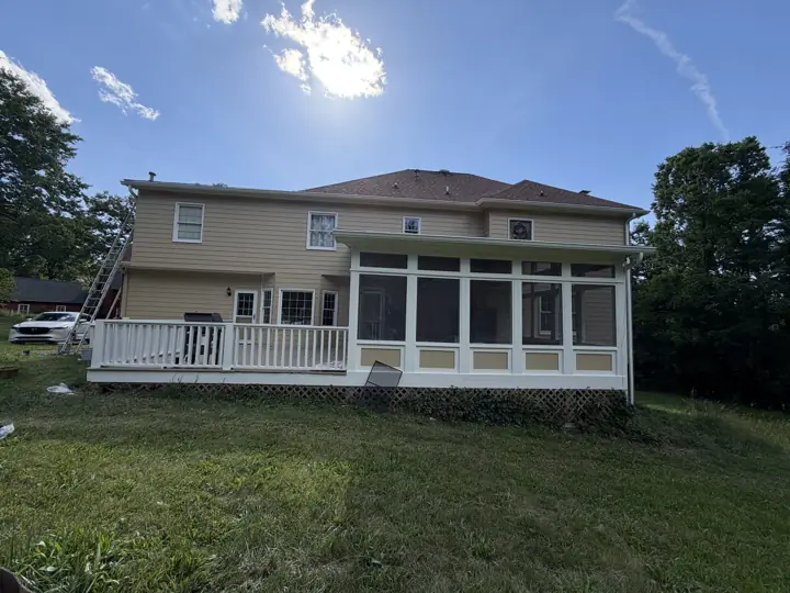 Full rear view of tan-sided home with white deck railings and screened porch in Signal Mountain, TN
