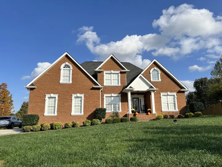 Front of red brick house with white arched window trim and columns in Ooltewah, TN