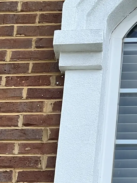Close-up of textured white window surround meeting red brick in Ooltewah, TN