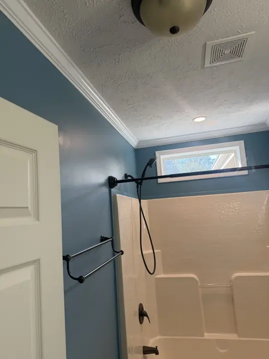 Deep blue bathroom walls with white crown molding above a tub and shower in Cleveland, TN