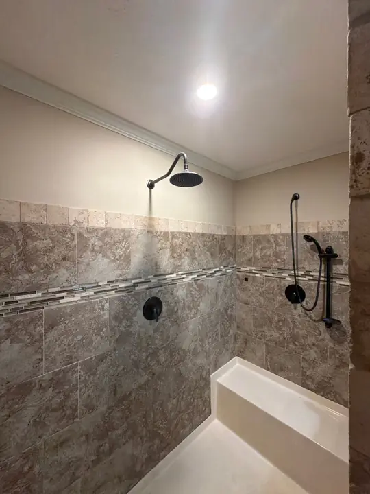 Walk-in shower with cream painted walls above stone tile and white crown molding in Cleveland, TN