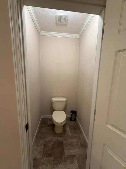 Small toilet room with cream walls, white crown molding and baseboards in Cleveland, TN