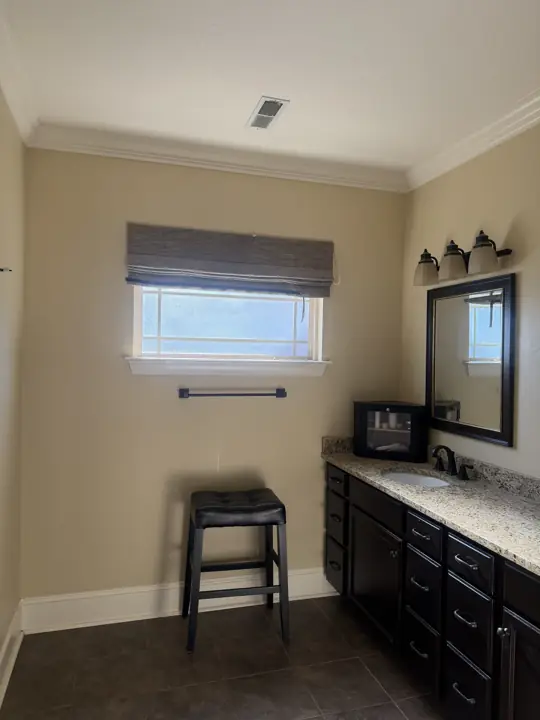 Bathroom window wall and dark vanity with white crown molding and baseboards in Hixson, TN