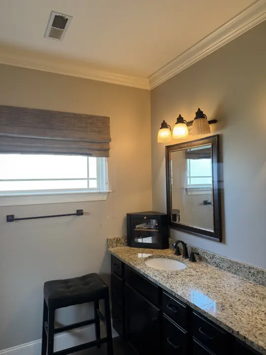 Bathroom with greige walls, white crown molding and dark vanity with granite top in Hixson, TN