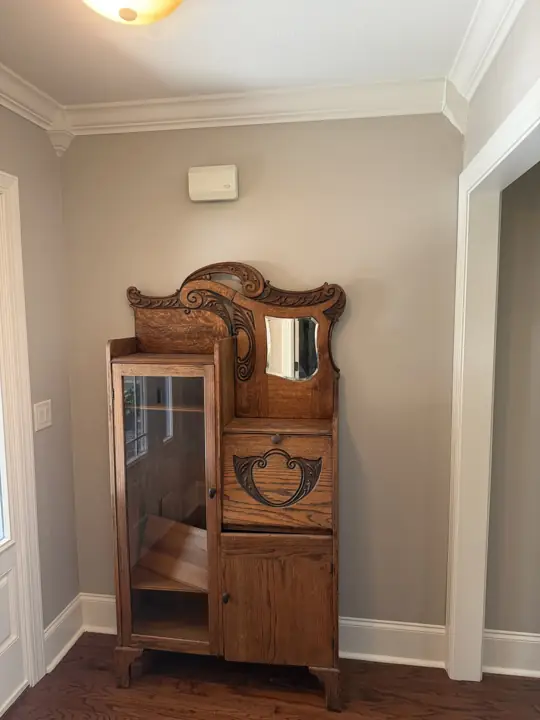 Entry hall with greige walls, white crown molding and an antique oak cabinet in Hixson, TN
