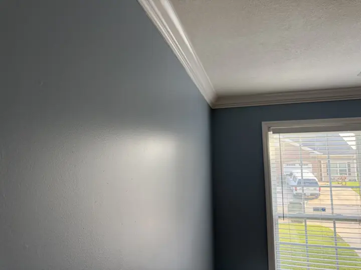 Close-up of slate blue wall meeting white crown molding and textured ceiling, Chattanooga, TN