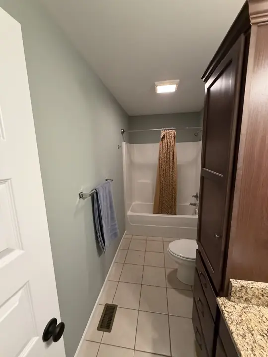 Hall bathroom in sage green with white tub surround and tile floor in Cleveland, TN