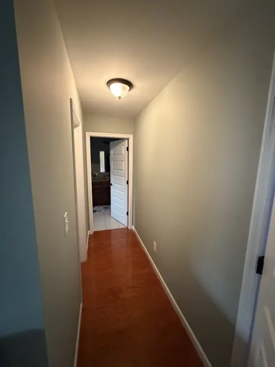 Narrow hallway with painted walls and white baseboards leading to a bathroom in Cleveland, TN