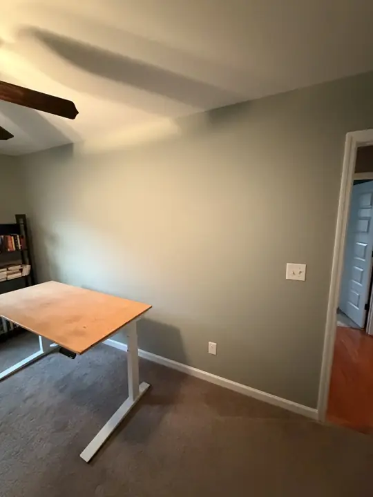 Sage green office wall with white baseboard and door casing in Cleveland, TN