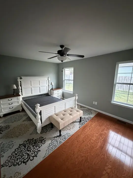 Bedroom with soft sage green walls, white baseboards and wood floor after interior painting in Cleveland, TN