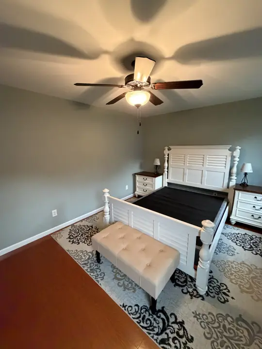 Sage green bedroom walls with white bed and ceiling fan in Cleveland, TN