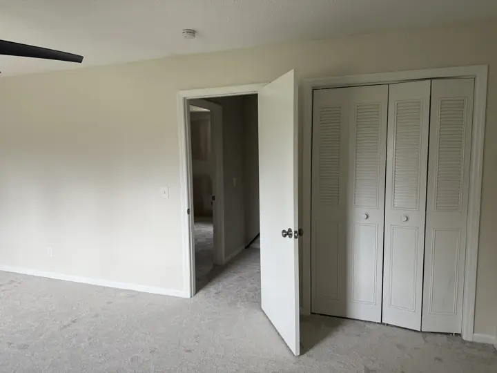 Cream bedroom with white door and louvered closet doors in Hixson, TN