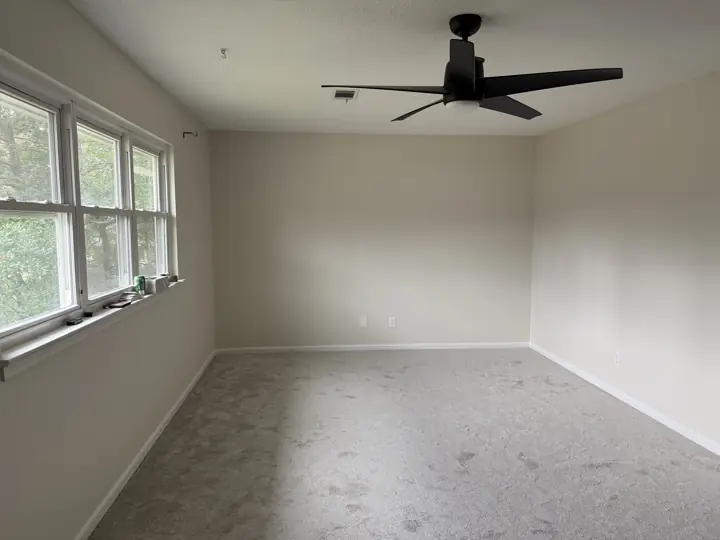 Cream bedroom with white baseboards and triple window after painting in Hixson, TN