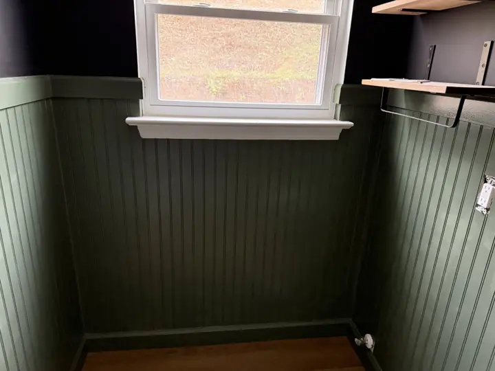 Forest green beadboard wainscoting below near-black walls with white window sill in Hixson, TN