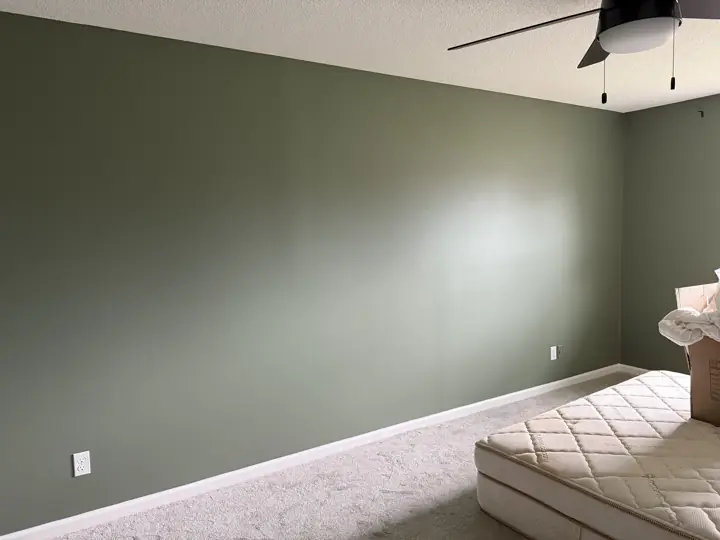 Long sage green bedroom wall with white baseboard in Hixson, TN