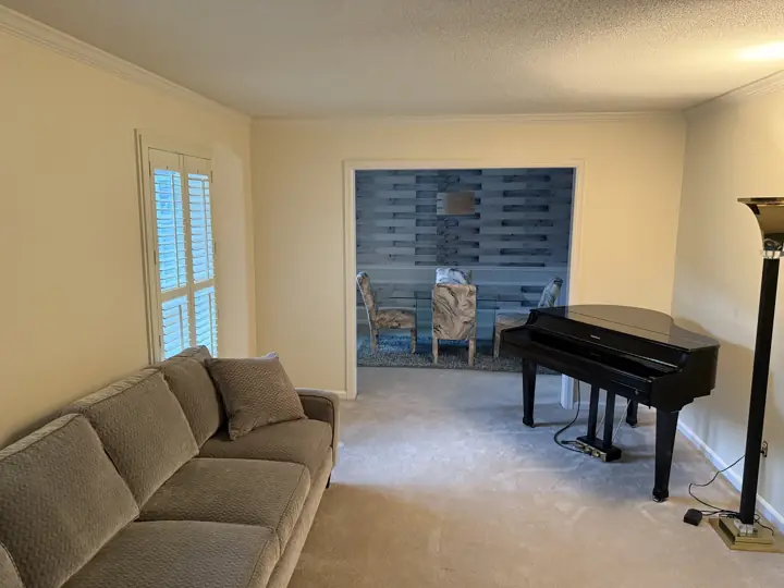 Cream living room with grand piano, white crown molding and view into gray dining room in Harrison, TN