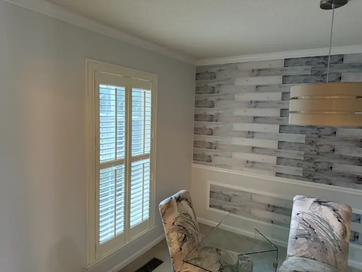 Light gray dining room wall beside plantation shutters and white crown molding in Harrison, TN