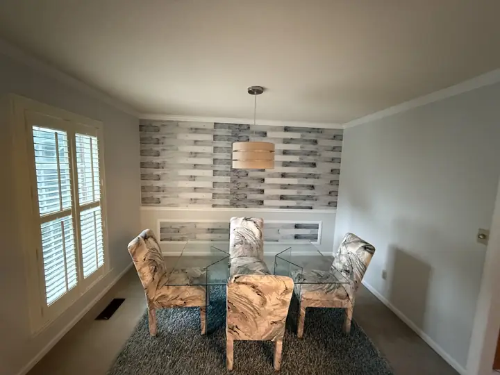 Pale gray dining room walls with white trim around a glass dining table in Harrison, TN