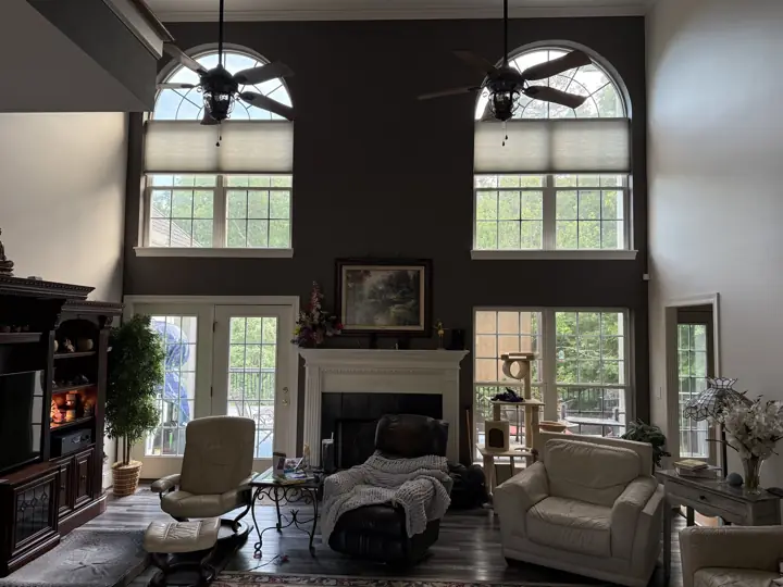 Two-story living room with charcoal-brown accent wall, arched windows and white mantel in Hixson, TN