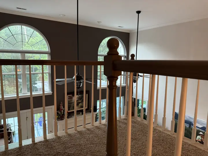 Loft railing overlooking a two-story living room with dark accent wall in Hixson, TN