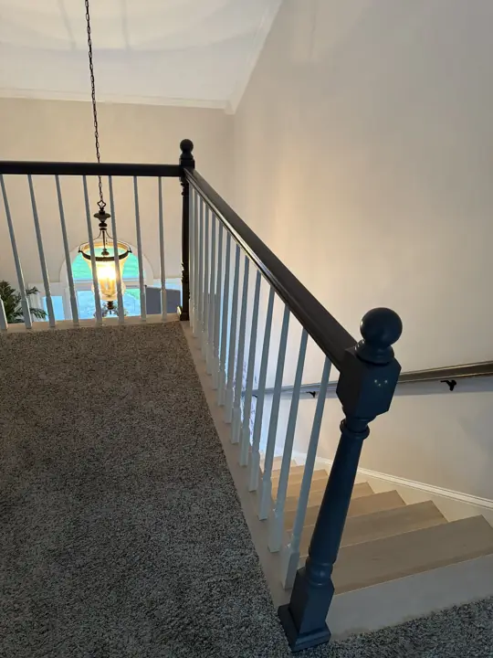 Loft railing with dark gray handrail and newel post at top of stairs in Hixson, TN