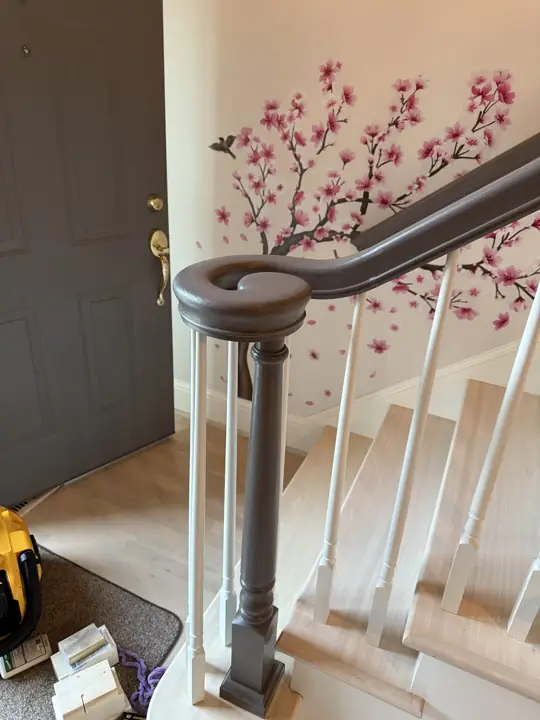 Gray-painted newel post and curled handrail beside a gray front door in Hixson, TN