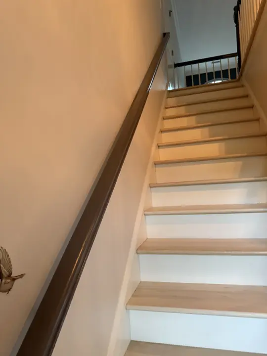 Staircase with gray wall-mounted handrail and warm white walls in Hixson, TN