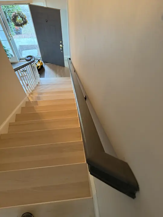 View down a staircase with gray wall handrail toward the front door in Hixson, TN
