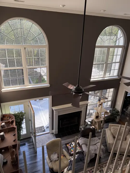 View down from the loft to a two-story living room with arched windows in Hixson, TN