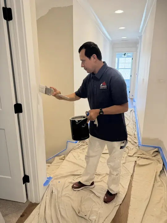 Painter cutting in a wall by brush in a taped, drop-clothed hallway, Soddy-Daisy, TN
