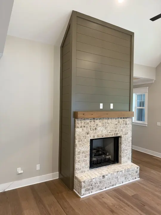 Tall olive shiplap chimney surround above a light brick fireplace and cedar mantel, Soddy-Daisy, TN