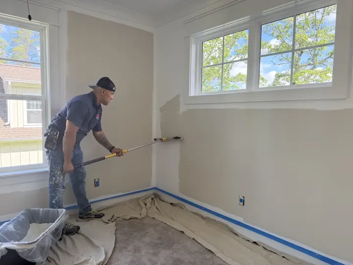 Painter rolling bedroom walls with taped baseboards and drop cloths, Soddy-Daisy, TN