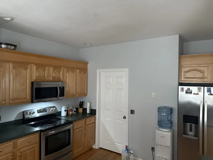 Kitchen with light blue-gray walls, white six-panel door and wood cabinets in Ooltewah, TN