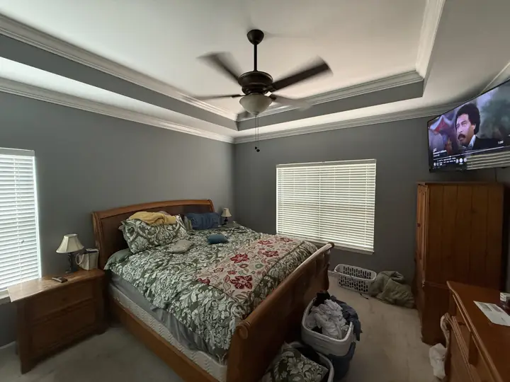 Wide view of gray primary bedroom with tray ceiling and white crown molding in Ooltewah, TN