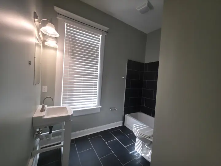 Bathroom with green-gray walls and white window trim next to dark tile after painting in Chattanooga, TN
