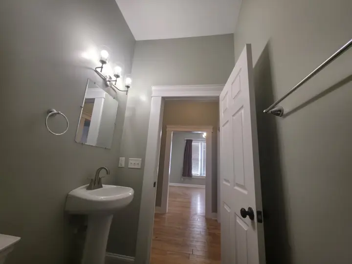 Bathroom with sage green walls, white door and casing beside pedestal sink in Chattanooga, TN
