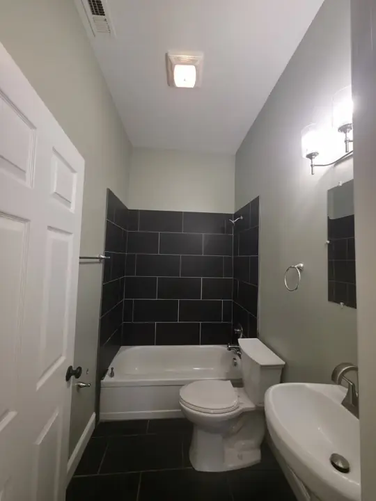 Bathroom with pale green walls and white ceiling beside dark tile tub surround in Chattanooga, TN