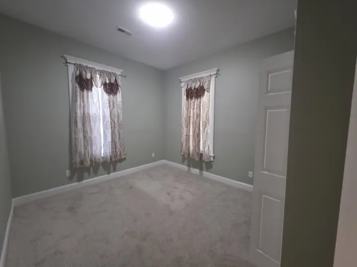 Carpeted bedroom with sage green walls and white trim after interior painting in Chattanooga, TN