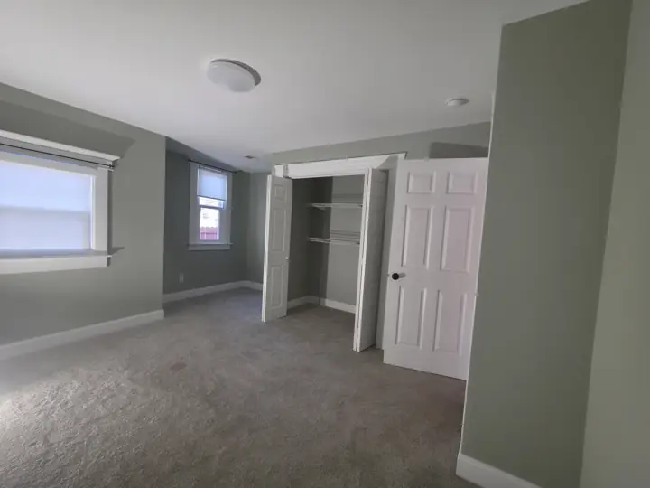 Sage green bedroom with white closet doors, window trim and baseboards in Chattanooga, TN