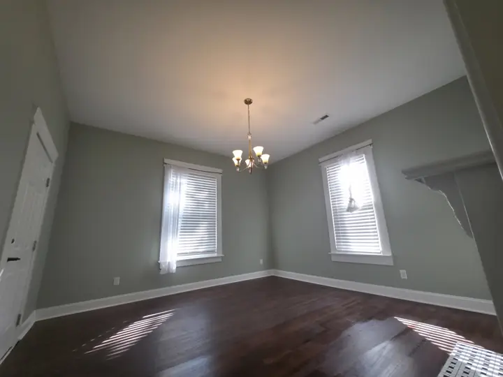 Sage green room with white window trim, baseboards and chandelier after interior painting in Chattanooga, TN